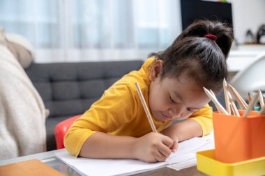 Asyalı genç kız ev ödevi yapıyor, evde çalışıyor..