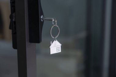Anahtarlığı olan anahtar kapı deliğinde ev şeklindeki bir anahtar..