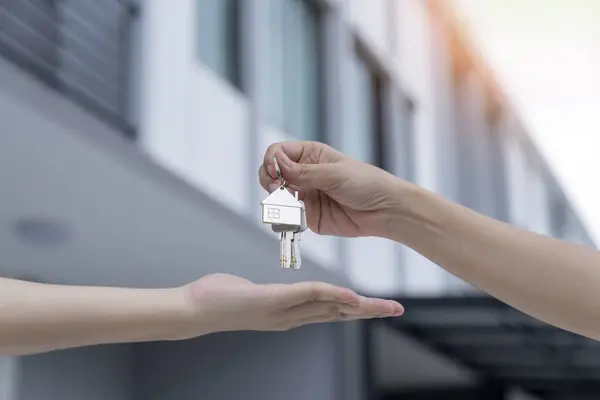 Real estate agent delivering keys house, Hands pass a house key as a symbol of real estate and house buying.