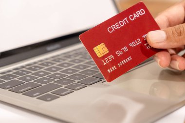 Online alışveriş için kredi kartı ve dizüstü bilgisayar kullanan adam