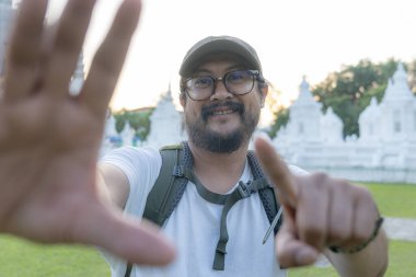 Asyalı adam seyahat ederken selfie çekiyor.