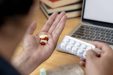 Uzun saatler masa başında çalıştıktan sonra ağrı kesici alan bir iş adamının arka görüntüsü.