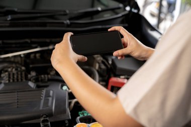 Arızalı arabasını tamir etmek için yol kenarından yardım isteyen bir kadın..