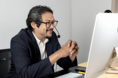 Çevrimiçi bir toplantıya katılırken kulaklık takan genç bir işadamı