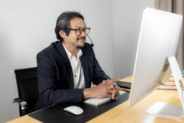 Çevrimiçi bir toplantıya katılırken kulaklık takan genç bir işadamı