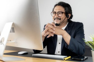 Çevrimiçi bir toplantıya katılırken kulaklık takan genç bir işadamı