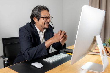 Modern takım çalışması, kulaklık takan bir erkek yönetici, profesyonel ofis ortamında iş arkadaşlarıyla proje planlarını aktif olarak tartışıyor.