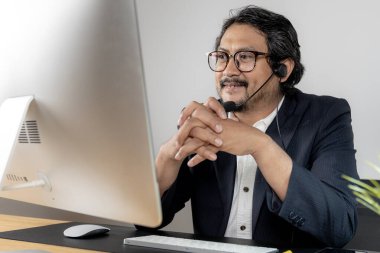 Modern takım çalışması, kulaklık takan bir erkek yönetici, profesyonel ofis ortamında iş arkadaşlarıyla proje planlarını aktif olarak tartışıyor.