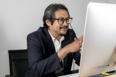 Modern takım çalışması, kulaklık takan bir erkek yönetici, profesyonel ofis ortamında iş arkadaşlarıyla proje planlarını aktif olarak tartışıyor.