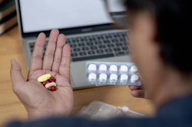 İşle ilgili yorgunluk, bir ofis çalışanı bilgisayarın başında uzun süre oturduğu için ağrı kesici almaya hazırlanır.