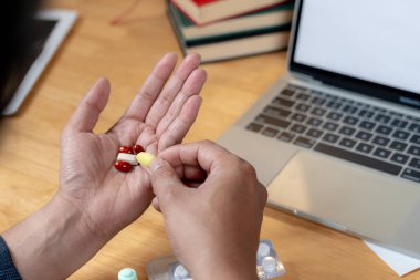 İşle ilgili yorgunluk, bir ofis çalışanı bilgisayarın başında uzun süre oturduğu için ağrı kesici almaya hazırlanır.