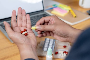 İşle ilgili yorgunluk, bir ofis çalışanı bilgisayarın başında uzun süre oturduğu için ağrı kesici almaya hazırlanır.