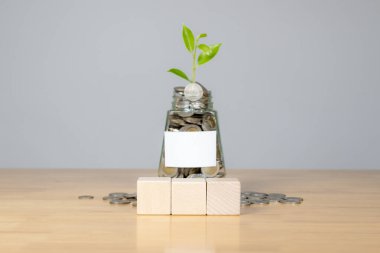 Bir kavanoz dolusu gümüş para biriktirmenin ve uzun vadeli yatırım hedeflerinin önemini temsil ediyor.