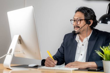 Video konferans görüşmesinde kulaklık takan odaklanmış bir çalışan..