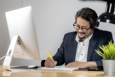 Video konferans görüşmesinde kulaklık takan odaklanmış bir çalışan..