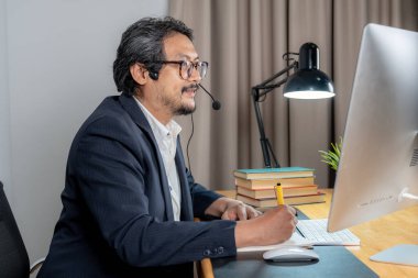 Video konferans görüşmesinde kulaklık takan odaklanmış bir çalışan..