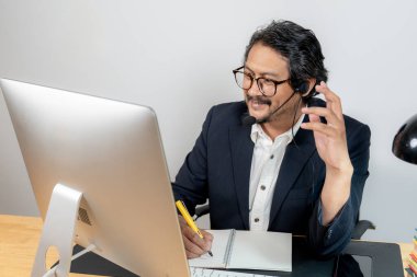 Modern ofis ortamında kulaklıkla sanal toplantıya katılan kendinden emin genç profesyonel