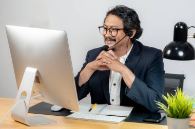 Modern ofis ortamında kulaklıkla sanal toplantıya katılan kendinden emin genç profesyonel