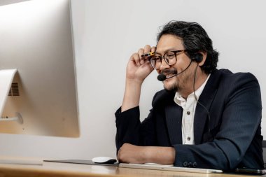 Mutlu ofis çalışanı kulaklık takıyor, modern çalışma yerinde sanal bir toplantının keyfini çıkarıyor..