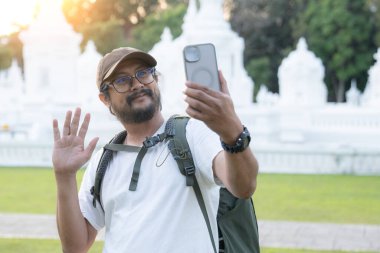 Genç Asyalı adam tek başına seyahat ederken özçekim yapmak için akıllı telefon kullanıyor, macera ve özgürlüğün tadını çıkarıyor..
