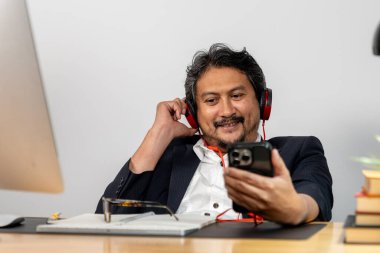 Kulaklık takan, müzik dinleyen ve iş arasında dinlenen genç ve mutlu bir ofis çalışanı..