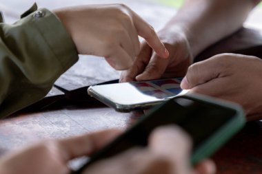 Bir grup insan akıllı telefonlar kullanıyor, modern iletişim ve teknolojiyi günlük hayatta sergiliyorlar..