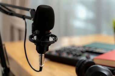 Bir mikrofon, kulaklık ve masa kurulumunun yer aldığı, dijital medya üretimi ve iletişimini sembolize eden yaratıcı bir podcast çalışma alanı.
