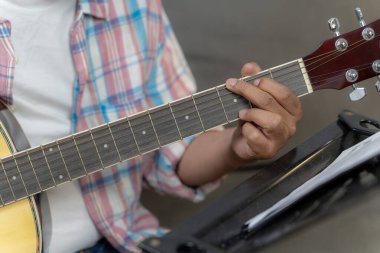 Gitar akorları oluşturan, müziği, yaratıcılığı ve sanatsal ifadeyi temsil eden bir adamın el hareketlerinin ayrıntıları..