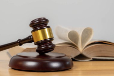 Arka planda bir yargıcın olduğu tokmağın yakın çekimi, hukuku, hukuki işlemleri, adaleti ve mahkeme otoritesini simgeliyor.