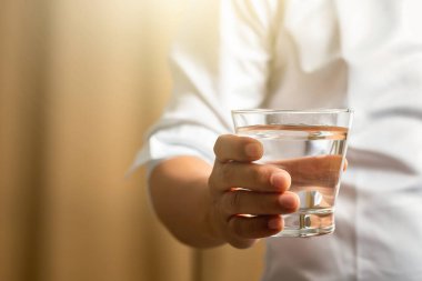 man holding glass of water,Man drinking a glass of water after work,A glass of water,female hand holding glass cup.