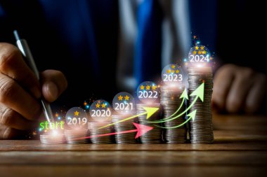 İşadamı para sikkelerini yukarı ok ve yıllık büyüme sembolü ile koyuyor. Banka artış faiz oranı veya iş büyümesi kavramından ipotek yatırımı .2023.2024