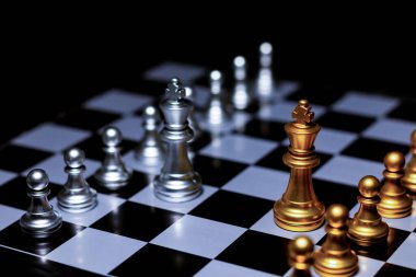 Satranç tahtasındaki gümüş satranç taşlarını altın satranç kralı yönetiyor. İş dünyası, başarı, rekabet, takım çalışması ve liderlik kavramı..
