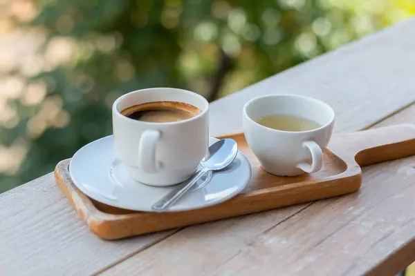 Wooden tray to hold empty coffee, coffee and water in a coffee shop.Hot black espresso coffee in the cup
