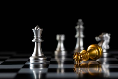 Satranç tahtasındaki gümüş satranç taşlarını altın satranç kralı yönetiyor. İş, başarı, rekabet, takım çalışması ve liderlik kavramı. Satranç, kral, altın, liderlik, taç.