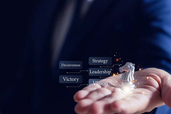 Бизнесмен, держащий серебряного шахматиста с ключевыми словами стратегия, лидерство, видение, символизирующие принятие решений, победу и бизнес-планирование.