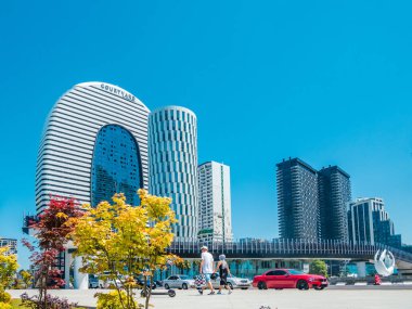 Ardagani Gölü yakınlarındaki dekoratif akçaağaçlar yeni bir yaya köprüsü ve modern binaların arka planına karşı.