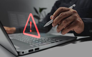 İşadamı, hata uyarısı için üçgen uyarı işareti olan dizüstü bilgisayar kullanıyor ve veri korumasını hackliyor.