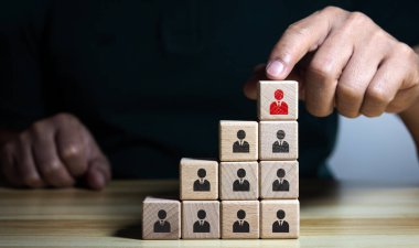 Tahta bloklardan oluşan piramitte elle insan ikonu topluyorlar. İşe alım ve personel seçimi konsepti. İnsan Kaynakları Yönetimi. Liderlik yeni lider ya da ekibin yeni çalışanı