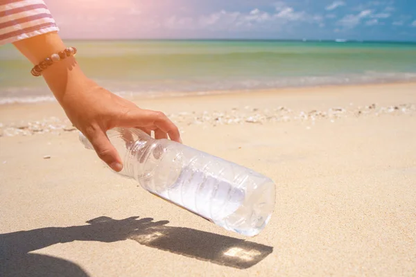 stock image Hand pick up empty water bottle or trash at beautiful beach. Environment Global warming issue.  