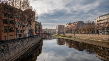 Colorful houses reflected in the Onyar river, in Girona, Catalonia, Spain. Church of Sant Feliu and Cathedral of Santa Maria in the background.