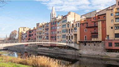 Colorful houses reflected in the Onyar river, in Girona, Catalonia, Spain. Church of Sant Feliu and Cathedral of Santa Maria in the background.
