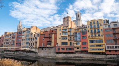 Colorful houses reflected in the Onyar river, in Girona, Catalonia, Spain. Church of Sant Feliu and Cathedral of Santa Maria in the background.
