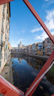 Colorful houses reflected in the Onyar river, in Girona, Catalonia, Spain. Church of Sant Feliu and Cathedral of Santa Maria in the background.