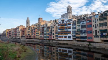 Colorful houses reflected in the Onyar river, in Girona, Catalonia, Spain. Church of Sant Feliu and Cathedral of Santa Maria in the background.