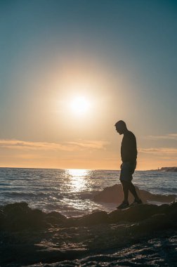 Silhouette of Man on the rocks watching the sunset.
