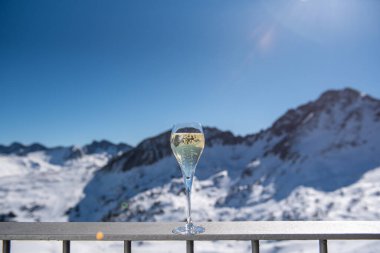 Arkasında karlı dağlar olan bir kadeh şampanya..