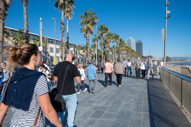 Barselona, İspanya: 19 Kasım 2023: İnsanlar Barceloneta plajı boyunca yürür Kışın güneşli bir günde Barcelona, İspanya 'da 2023 kışında Katalonya.