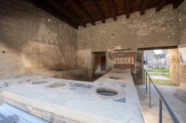 Pompeii, İtalya: 16 Kasım 2023: Antik Pompeii 'deki Antik bar tezgahı (UNESCO Dünya Mirası Alanı). Kasım 2023 'te Via del Foro' nun taşları..