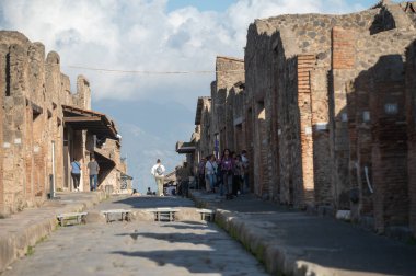 Pompeii, İtalya: 16 Kasım 2023: Antik Pompeii 'de yürüyen insanlar (UNESCO Dünya Mirası Alanı). Kasım 2023 'te Via del Foro' nun taşları..