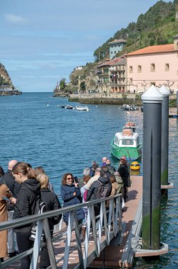 Pasaia, Spain: 2024 March 24: People boarding the ferry in the fishing and tourist town of Pasaia in the Province of Guipuzcoa in March 2024. clipart